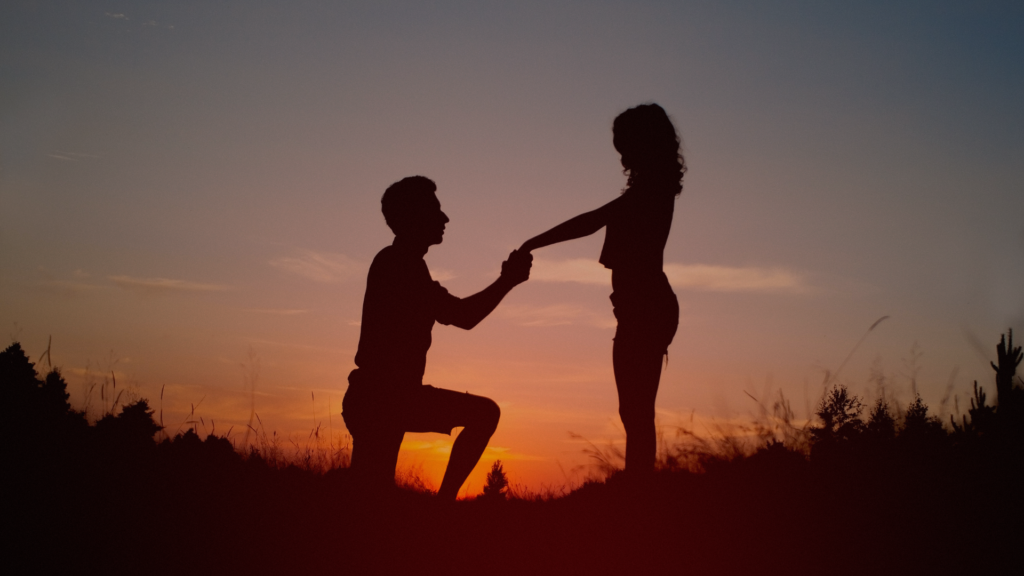 Uma silhueta de um casal ao pôr do sol, com um homem ajoelhado segurando as mãos de uma mulher, simbolizando reconciliação, compromisso e transformação espiritual, resumindo: que o casamento não acabou.  