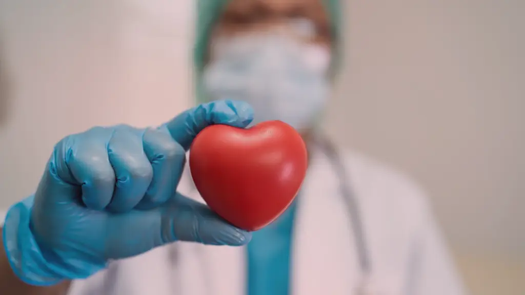 Médico ou profissional da saúde segurando um pequeno coração vermelho nas mãos usando luvas cirúrgicas, simbolizando cuidado e atenção com a saúde emocional e afetiva. A imagem transmite a ideia de que a compulsão emocional é uma condição que merece ser tratada com seriedade e atenção profissional. 