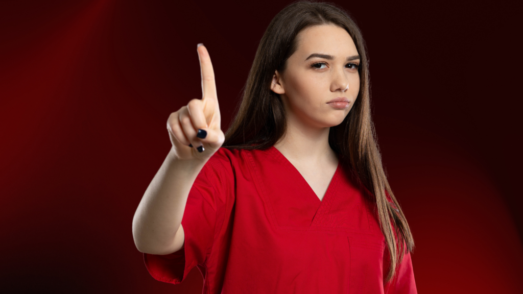 Mulher jovem vestindo roupa vermelha faz sinal de "pare" com o dedo indicador levantado, expressando firmeza e desaprovação, simbolizando quando não insistir em um relacionamento difícil. O fundo vermelho intenso reforça o tom de alerta, indicando limites e decisão. 