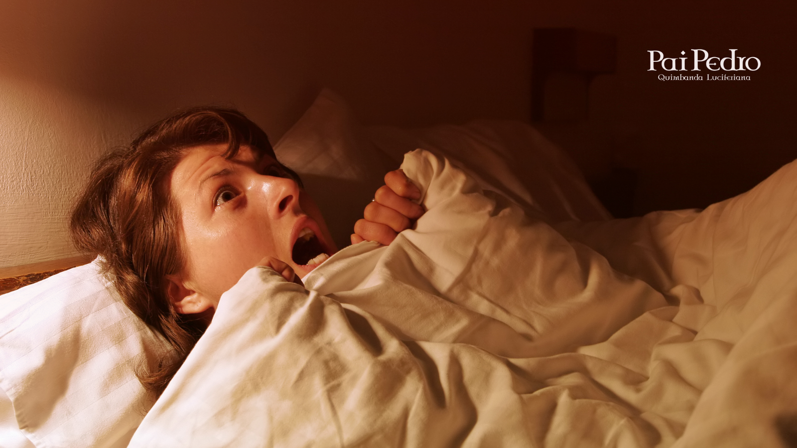 Mulher assustada acordando de um pesadelo, com expressão de pânico e suor no rosto, envolta em cobertores, em um quarto escuro iluminado por luz quente. Representa o impacto emocional de sonhar com separação.