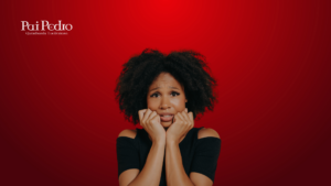 Mulher negra de cabelos cacheados está com expressão de insegura e medo, com as mãos próximas ao rosto em sinal de tensão. O fundo é vermelho intenso, e no canto superior esquerdo está o logotipo "Pai Pedro - Quimbanda Luciferiana".