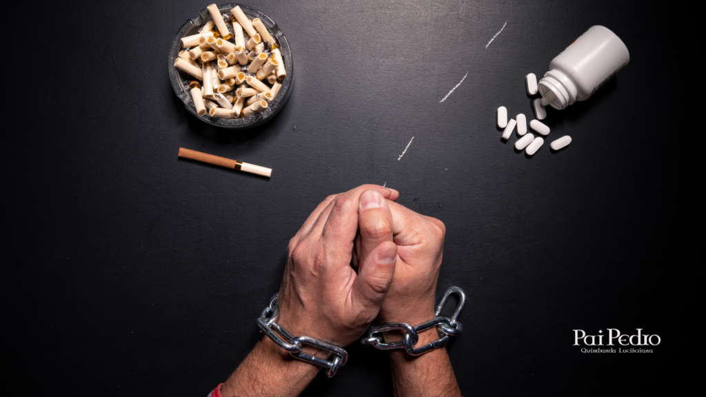 Imagem impactante com fundo escuro. No centro, mãos humanas estão unidas em forma de oração, mas presas por correntes grossas de metal, simbolizando aprisionamento e desespero. Ao redor das mãos, há um cinzeiro cheio de bitucas de cigarro, uma fileira de pó branco (aludindo a drogas ilícitas) e um frasco aberto com diversos comprimidos espalhados, representando vício e autodestruição. No canto inferior direito, está o nome “Pai Pedro — Quimbanda Luciferiana”, indicando o contexto espiritual da imagem.
