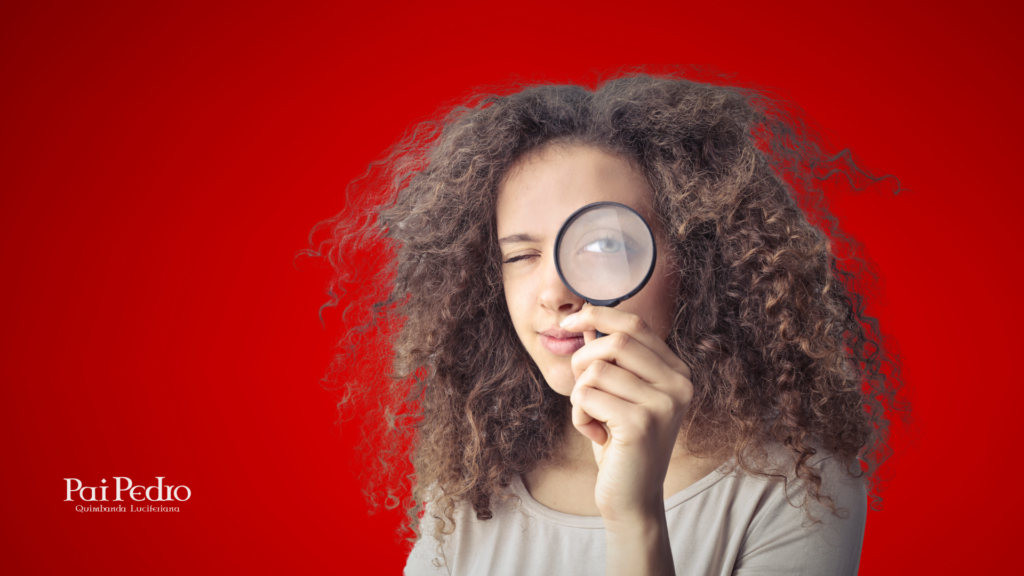 Mulher de cabelos cacheados e expressão investigativa observa atentamente com uma lupa, simbolizando a busca por pistas, Sinais de que Seu Marido Está Tendo um Relacionamento Extraconjugal. O fundo vermelho vibrante remete a tensão e urgência. No canto inferior esquerdo, está a marca "Pai Pedro – Quimbanda Luciferiana".